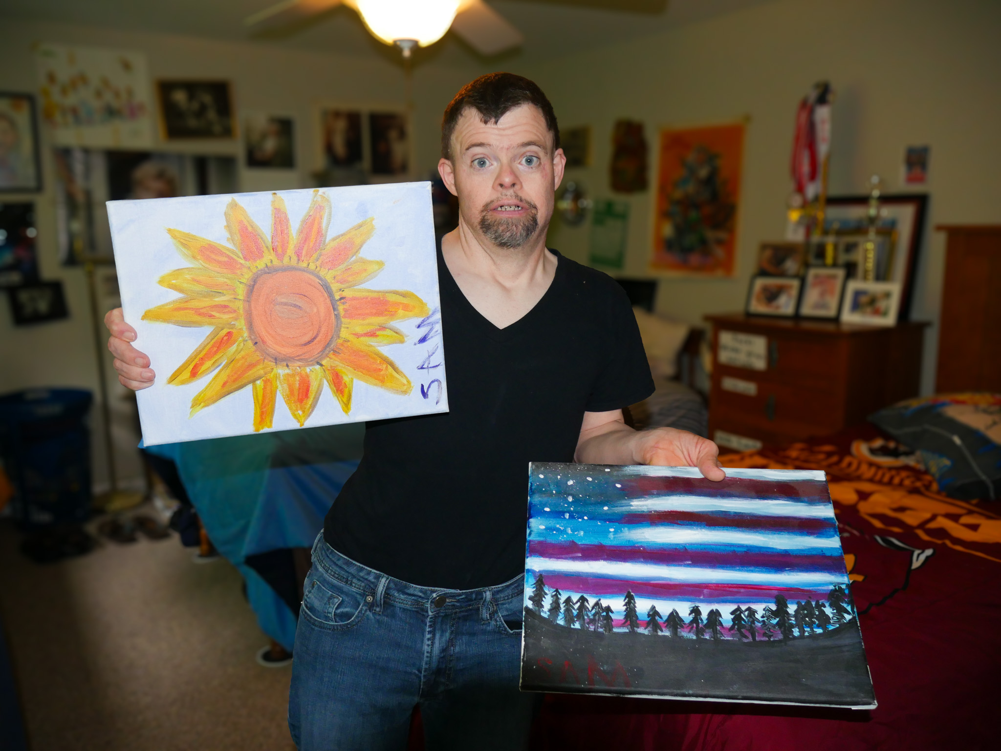 Gabriel Homes resident holding two canvases they painted.