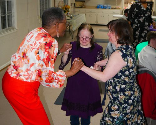 Marlene (left), residential counselor at Gabriel Homes, dancing with two residents (center and right).