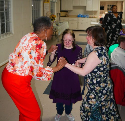 Marlene (left), residential counselor at Gabriel Homes, dancing with two residents (center and right).