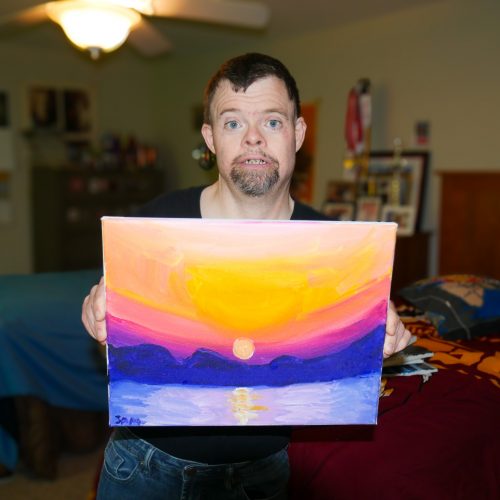 Gabriel Homes resident holding a canvas they painted.
